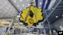 FILE - In this photo provided by NASA, technicians lift the mirror of the James Webb Space Telescope using a crane, April 13, 2017, at the Goddard Space Flight Center in Greenbelt, Md. 