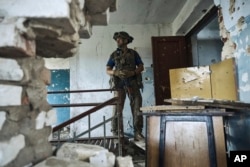 A Ukrainian soldier examines a culture center in recently retaken in Blahodatne, Donetsk region, Ukraine, June 16, 2023.
