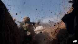 A Ukrainian soldier of the 28th Brigade fires a grenade launcher on the front line during a battle with Russian troops near Bakhmut, Donetsk region, Ukraine, March 24, 2023.