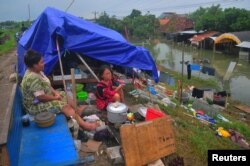 Masyarakat beristirahat di tenda darurat seiring ditundanya pemungutan suara pemilu di 10 desa di Kabupaten Karanganyar yang terdampak banjir Sungai Wulan, di Demak, Jawa Tengah, Indonesia 14 Februari 2024. (Antara Foto/Yusuf Nugroho via REUTERS)