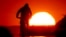 A man rides a bike on a small road on the outskirts of Frankfurt, Germany, as the sun rises on July 7, 2023.