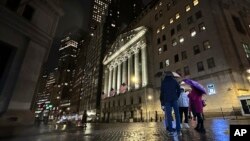 People huddle outside the New York Stock Exchange on Nov. 21, 2023, in New York.