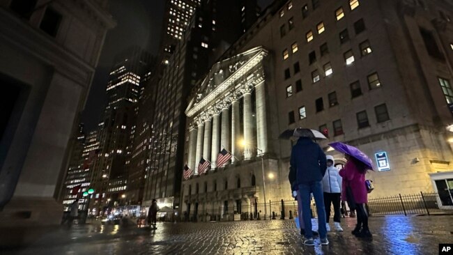 People huddle outside the New York Stock Exchange on Nov. 21, 2023, in New York.