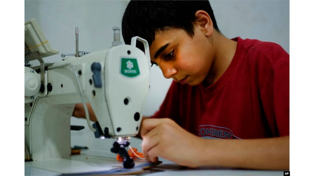FILE - Ahmad Abo Baker, a Syrian refugee child, works at a shoe workshop in Gaziantep, Turkey, June 2, 2016. When the photo was taken, Ahmad worked 12 hours a day, six days a week, along with his father, and he was paid 100 Turkish liras per week.