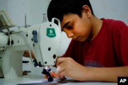 FILE - Ahmad Abo Baker, a Syrian refugee child, works at a shoe workshop in Gaziantep, Turkey, June 2, 2016. When the photo was taken, Ahmad worked 12 hours a day, six days a week, along with his father, and he was paid 100 Turkish liras per week.