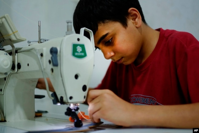 FILE - Ahmad Abo Baker, a Syrian refugee child, works at a shoe workshop in Gaziantep, Turkey, June 2, 2016. When the photo was taken, Ahmad worked 12 hours a day, six days a week, along with his father, and he was paid 100 Turkish liras per week.