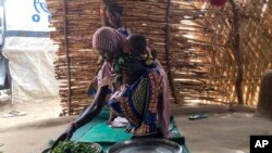 FILE - Iza Ali, 25, prepares a meal at the Jere camp for displaced people in Maiduguri, Nigeria, May 4, 2022. Nigeria declared a national emergency on food security July 13, 2023, as record inflation has made basic foods unaffordable for many.