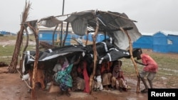 Sudanese people, who fled the conflict in Sudan's Darfur region, sit at their makeshift shelter during a rainstorm at a refugee camp in Ourang on the outskirts of Adre, Chad, July 30, 2023.