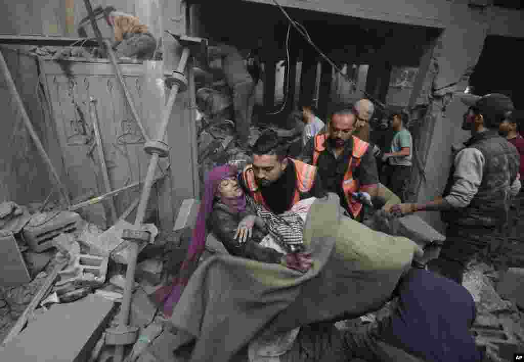 Palestinian rescuers evacuate an injured woman that was found under the rubble of a destroyed house following an Israeli airstrike in Khan Younis refugee camp, southern Gaza Strip, Nov. 18, 2023. 
