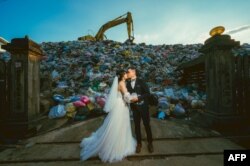 Iris Hsueh dan tunangannya berfoto di depan tumpukan sampah yang menggunung di Nantou County, Taiwan, 14 Oktober 2023. (Foto: Owen Kang/via Reuters)