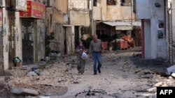 İsrail'in "terör operasyonu" olarak adlandırdığı Batı Şeria'nın kuzeyindeki Cenin mülteci kampına yönelik askeri operasyonun ardından bir çift harabeye dönmüş sokakta yürüyor- 5 Temmuz 2023