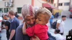  ایک فلسطینی خاتون اپنے بیمار بچے کو خان یونس علاج کے لیے بھیجنے سے قبل اسے خدا حافظ کہہ رہی ہے، فوتو اے پی 27 جون 2024