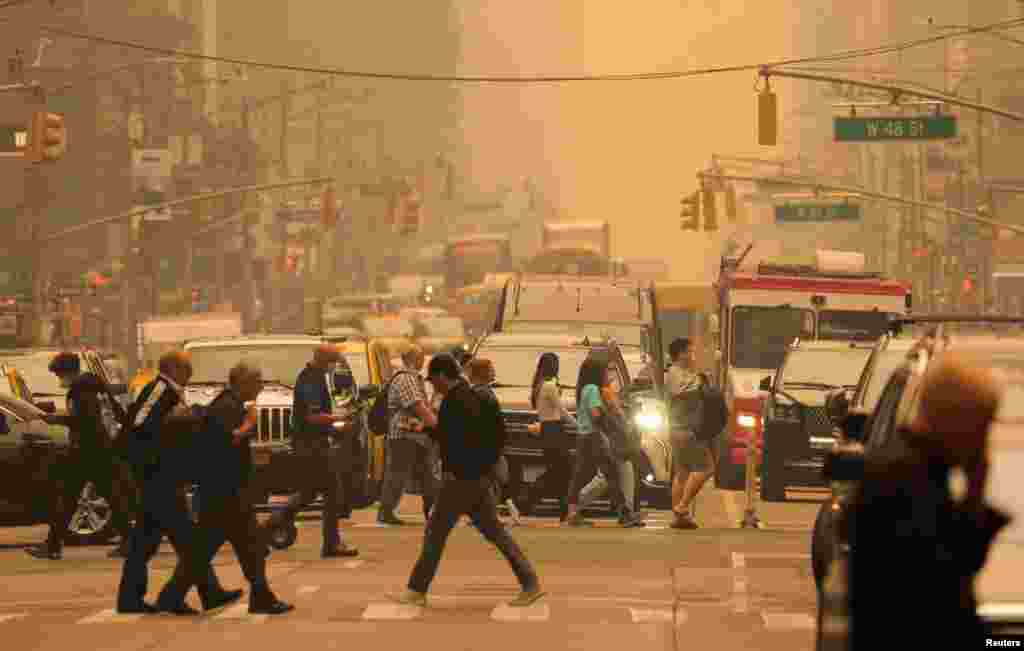 People walk at 6th Avenue as haze and smoke caused by wildfires in Canada blanket New York City, June 7, 2023.