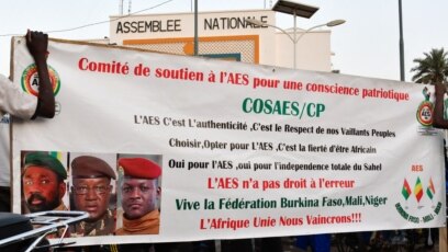 Des partisans de l'Alliance des États du Sahel (AES) brandissent leur bannière alors qu'ils célèbrent le départ du Mali, du Burkina Faso et du Niger de la Communauté économique des États de l'Afrique de l'Ouest (CEDEAO), à Niamey, le 28 janvier 2024. (Photo HAMA BOUREIMA / AFP)