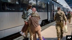 Seorang tentara Ukraina memeluk anak dan istrinya di stasiun kereta api di Sloviansk, Ukraina, pada 12 September 2023. Tentara tersebut akan menaiki kereta untuk berangkat menuju garis depan pertempuran di Kramatorsk. (Foto: AP/Hanna Arhirova)