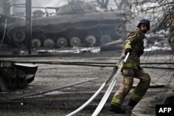 Arhiva - Ukrajinski vatroasac vuče crevo tokom rada na gašenju požara na benzinskoj pumpi, pogođenoj u ruskom udaru na Kostjantinivku, region Donjecka, 22. jula 2023.