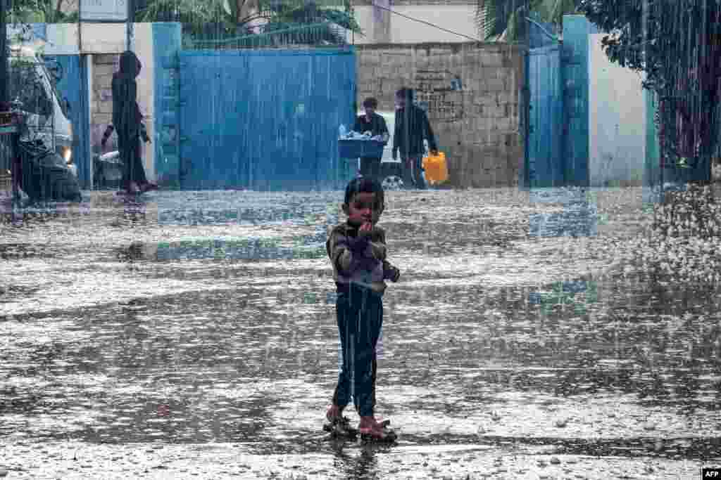 A boy stands in the rain at a school run by the United Nations Relief and Works Agency for Palestine Refugees in the Near East (UNRWA) in Rafah in the southern Gaza Strip.