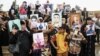 FILE - Iraqis hold up portraits of missing relatives who were held captive by Islamic State group fighters during a demonstration in Mosul on April 13, 2018. 