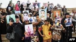 FILE - Iraqis hold up portraits of missing relatives who were held captive by Islamic State group fighters during a demonstration in Mosul on April 13, 2018. 