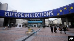 FILE - People walk under a banner advertising the European elections outside the European Parliament in Brussels, on Jan. 24, 2024. 