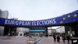 ARCHIVO - Personas caminan bajo una pancarta que anuncia las elecciones europeas frente al Parlamento Europeo en Bruselas, el 24 de enero de 2024.