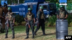 Army soldiers stand guard during a protest by Sri Lankan rights activists outside the main cemetery in Colombo, July 23, 2023. Sri Lanka tightened security Sunday as activists lit lamps in Colombo to honor hundreds killed in 1983 anti-Tamil riots.