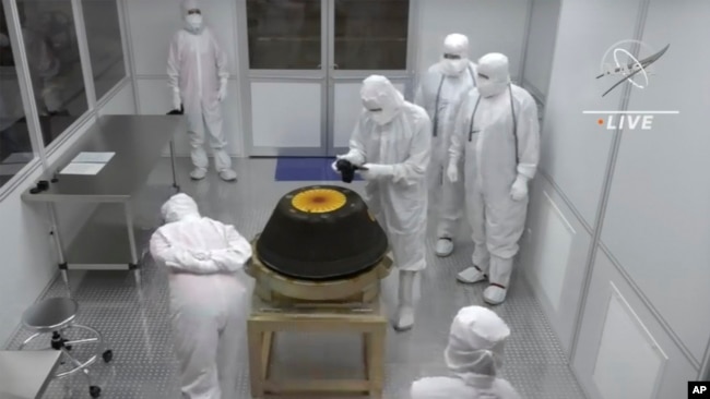 In this NASA image, technicians in a clean room examine the sample return capsule from the Osiris-Rex mission after it landed in the Utah desert on Sunday, Sept. 24, 2023. (NASA via AP)