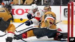El pívot de los Florida Panthers, Aleksander Barkov, centro, intenta superar al portero de Golden Knights, Adin Hill, mientras el defensa Alex Pietrangelo ayuda a defender en el Juego 5 de las Finales de la Copa Stanley de hockey de la NHL en Las Vegas, el 13 de junio de 2023.