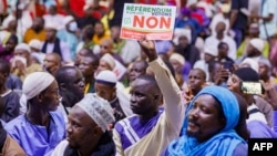 A man holds up a sign that reads 'vote no on the referendum' during a march against the new constitution organized by the Association of Imams, in Bamako, on June 16, 2023. 