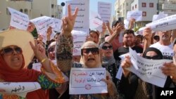 FILE: People lift placards as they shout slogans during a demonstration against the presence of illegal sub-Saharan migrants, in Sfax on June 25, 2023. Sfax, the second largest city in Tunisia, is the starting point for a large number of illegal migrants trying to reach Italy.