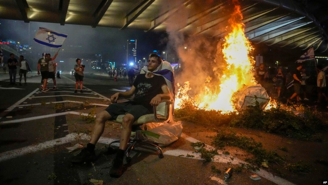 A bonfire burns as Israelis occupy the Ayalon Highway to protest against plans by Prime Minister Benjamin Netanyahu's government to overhaul the judicial system, in Tel Aviv, July 20, 2023.