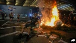 A bonfire burns as Israelis occupy the Ayalon Highway to protest against plans by Prime Minister Benjamin Netanyahu's government to overhaul the judicial system, in Tel Aviv, July 20, 2023.