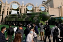 FILE - Visitors tour past military vehicles carrying the Dong Feng 41 and DF-17 ballistic missiles at the Beijing Exhibition Hall in Beijing on Oct. 12, 2022. (AP Photo/Andy Wong)