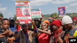 Family, friends and fellow protesters carry a photo of Rex Masai, who was shot by the police during Kenya's anti-finance bill protest, as they chant slogans to show their respects during his burial in Machakos County, Kenya, on July 5, 2024. 