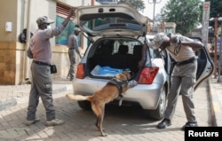 Private security guards use a dog to search a car before entering the Westgate shopping mall, on the 10th commemoration since the Somali militant group al-Shabaab attacked the mall killing at least 67 people, in Nairobi, Kenya, Sept. 21, 2023.