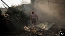 A woman walks outside her burning house after a Russian attack in Kherson, Ukraine, June 9, 2023. 