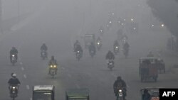 Commuters make their way along a street amid dense smog in Lahore, Pakistan.