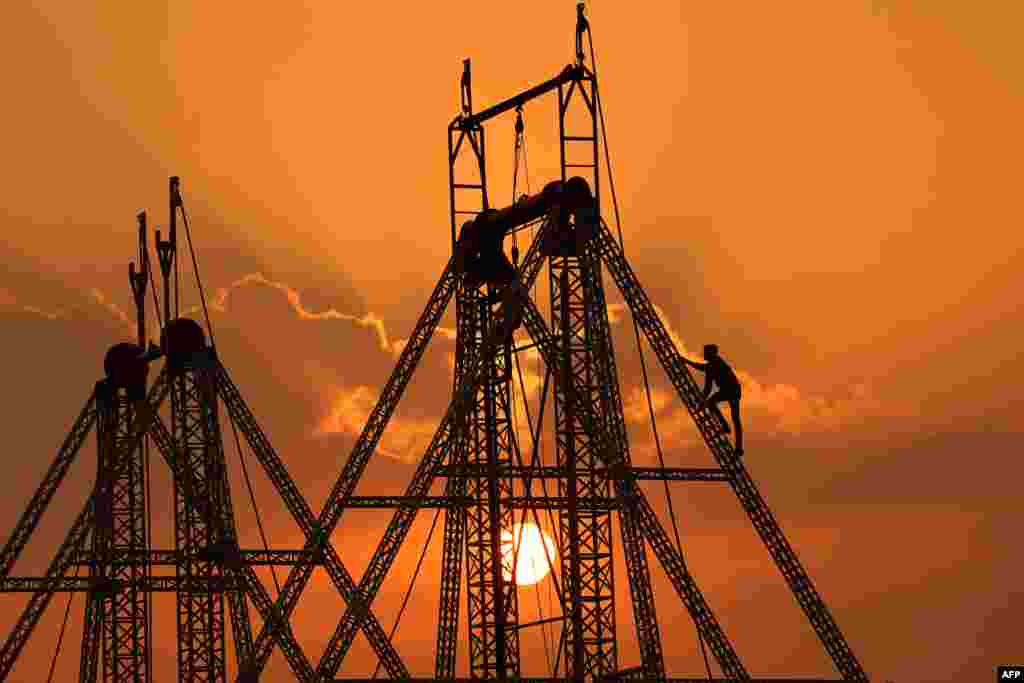 A laborer is silhouetted against the setting sun as he works on a swing at a fair ground in Pushkar, Pakistan.