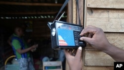 FILE - A man tunes a small radio set to listen to news at a busy local marketplace stall in Harare, Zimbabwe, Feb. 2, 2023.