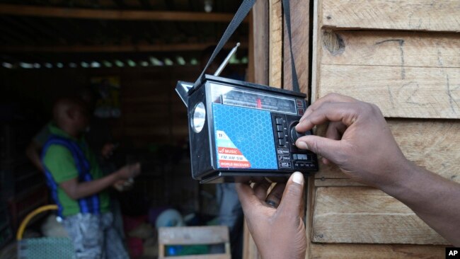 FILE - A man tunes a small radio set to listen to news at a busy local marketplace stall in Harare, Zimbabwe, Feb. 2, 2023.