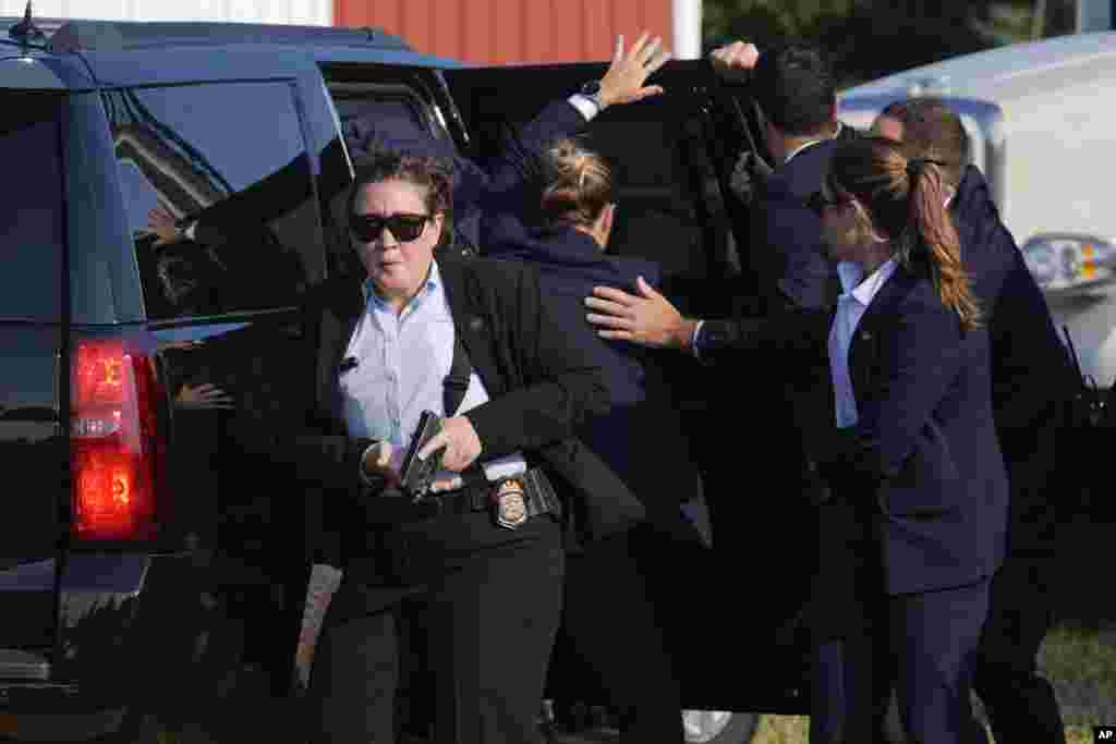 Donald Trump is surrounded by Secret Service agents as he is taken to a vehicle.