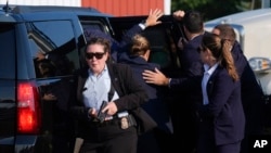 Republican presidential candidate former President Donald Trump is surrounded by Secret Service agents as he is taken to a vehicle at a campaign rally, July 13, 2024, in Butler, Pennsylvania.