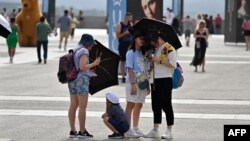 Turis berlindung dari terik matahari dengan payung di depan Istana Kerajaan di Madrid pada 18 Juli 2023. (Foto: AFP)