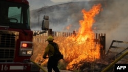 Seorang petugas pemadam kebakaran mendekati api saat kebakaran di Riverside County, California, 14 Juli 2023, sebagai ilustrasi. Enam orang, termasuk tiga anak-anak, tewas dalam kebakaran yang menghancurkan sebuah rumah di barat daya Atlanta. (Foto: AFP)