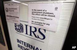 FILE - A sign advises that the office will be closed during the partial government shutdown on doors at the Internal Revenue Service (IRS) in the Henry M. Jackson Federal Building in Seattle, Jan. 16, 2019.