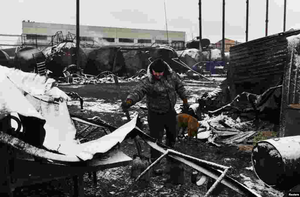 Маж ја проверува штетата во складиштето за нафта погодено од неодамнешното гранатирање во Доњецк, Украина под руска контрола.