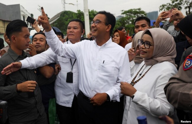 Calon presiden Anies Baswedan menunjukkan jarinya yang berlumuran tinta usai memberikan suaranya di TPS bersama istrinya Fery Farhati Ganis, pada hari pemilihan umum di Jakarta, 14 Februari 2024. (REUTERS/Ajeng Dinar Ulfiana)