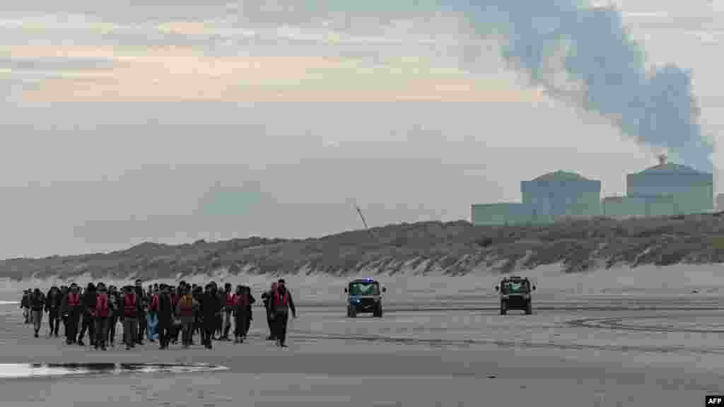 Para migran kembali ke pedalaman setelah dicegah menaiki perahu penyelundup oleh Polisi Nasional Prancis di pantai Gravelines, Prancis utara.