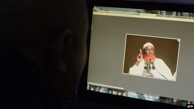 FILE - A man looks at a computer screen displaying an image of Somali-born cleric and Islamic State-Somalia leader Abdulkadir Mumin, in Nairobi, Kenya, Sept. 1, 2016.