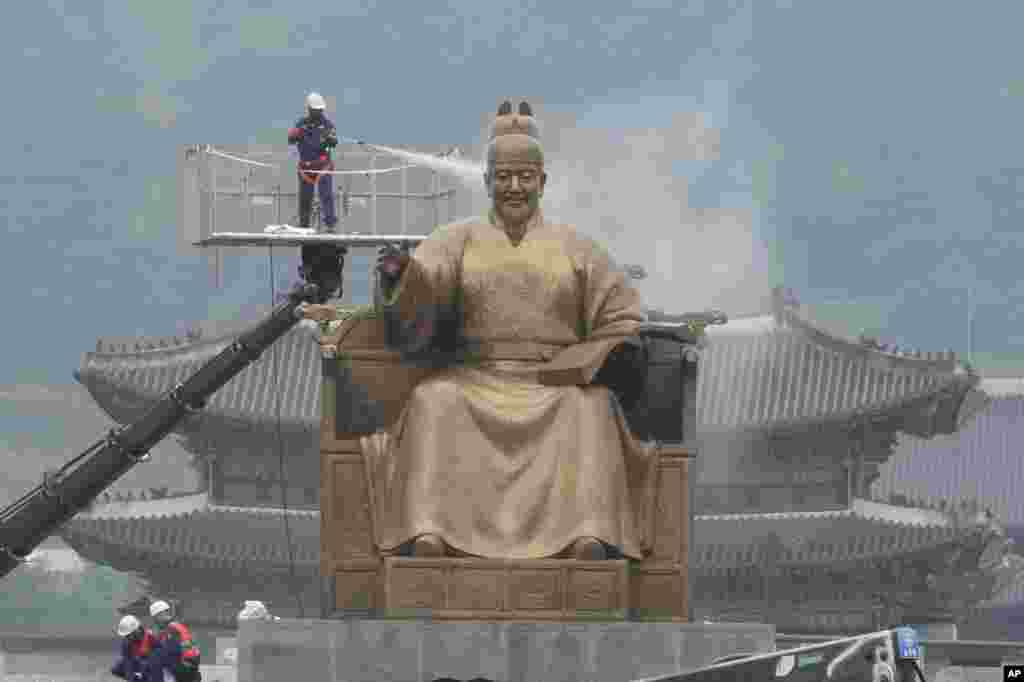 Seorang pekerja menyemprotkan air ke patung Raja Sejong pada saat pembersihan patung tersebut di Gwanghwamun Plaza di ibu kota Seoul, Korea Selatan. (AP)&nbsp;